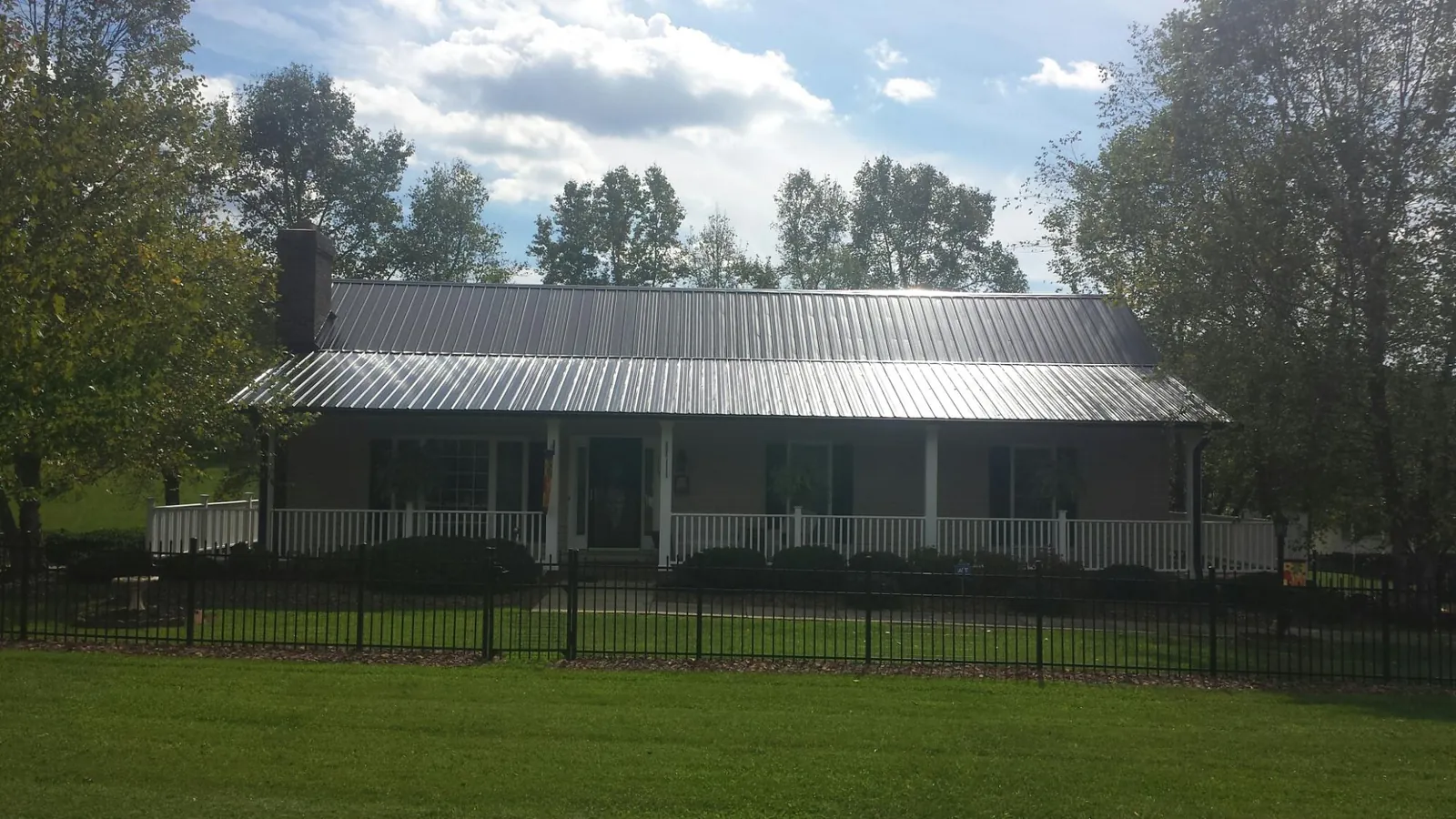 Gray metal roof on a brick ranch with a full width front porch — Gutter Guard Installation work by our crew in Sandusky