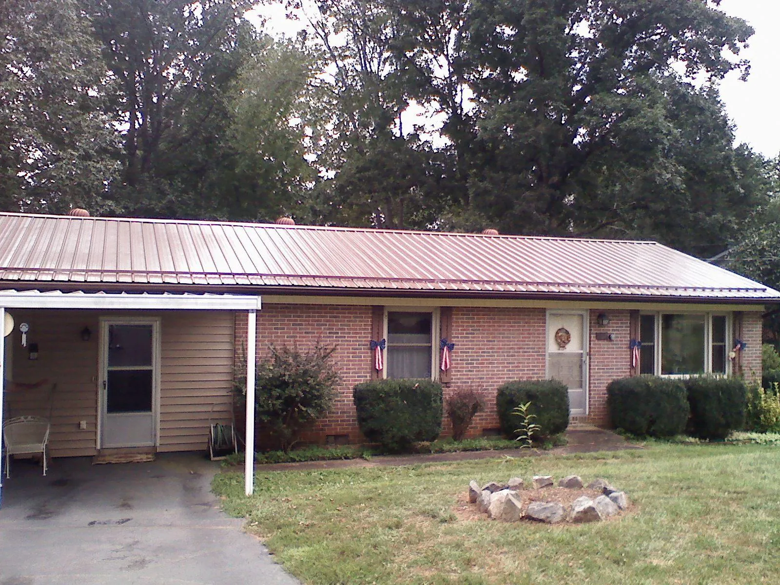 Bronze metal roof and carport on a brick ranch home — Roof Repair work by our crew in Sandusky